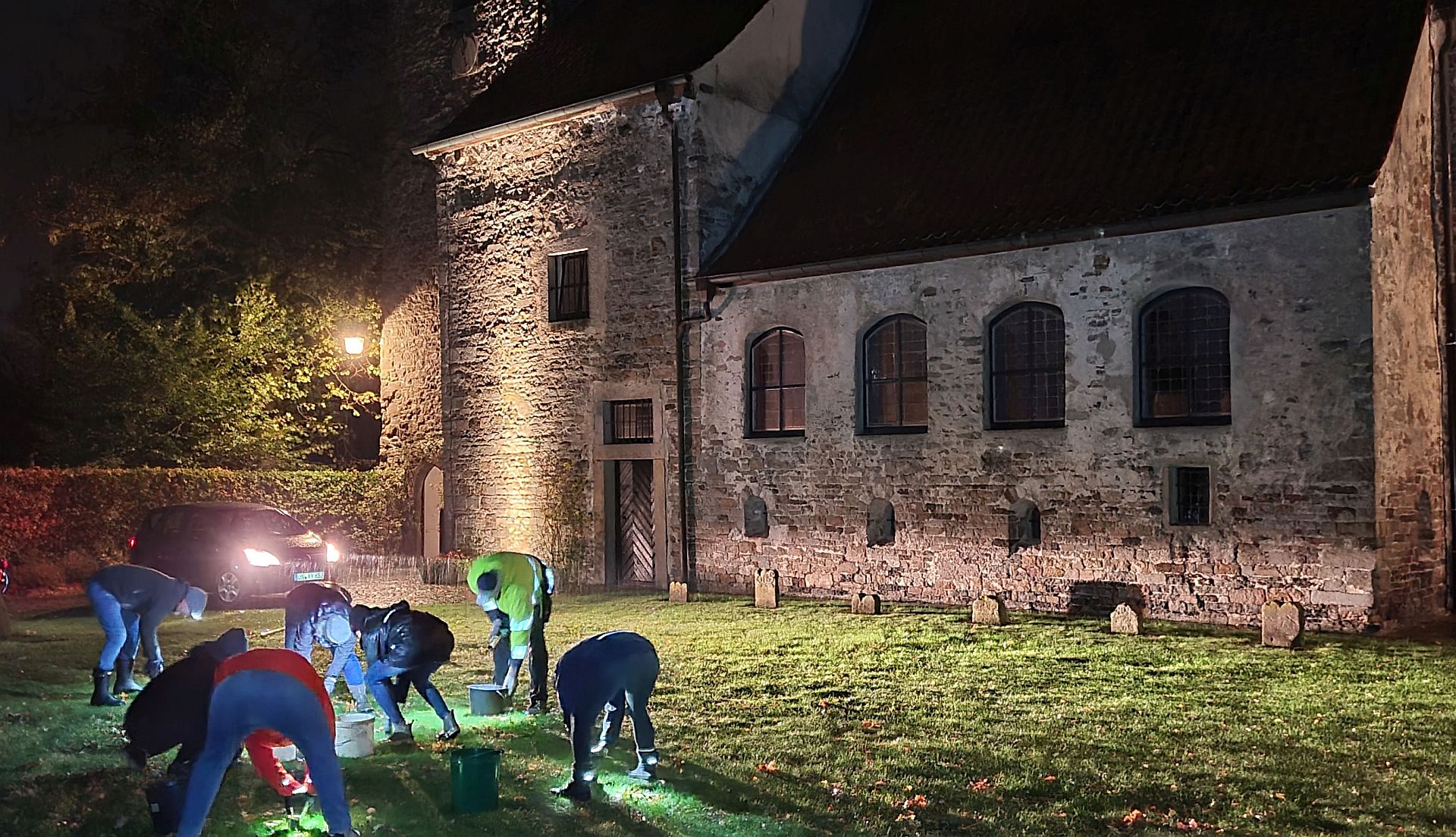 Menschen pflanzen Krokusse vor der Alten Kirche